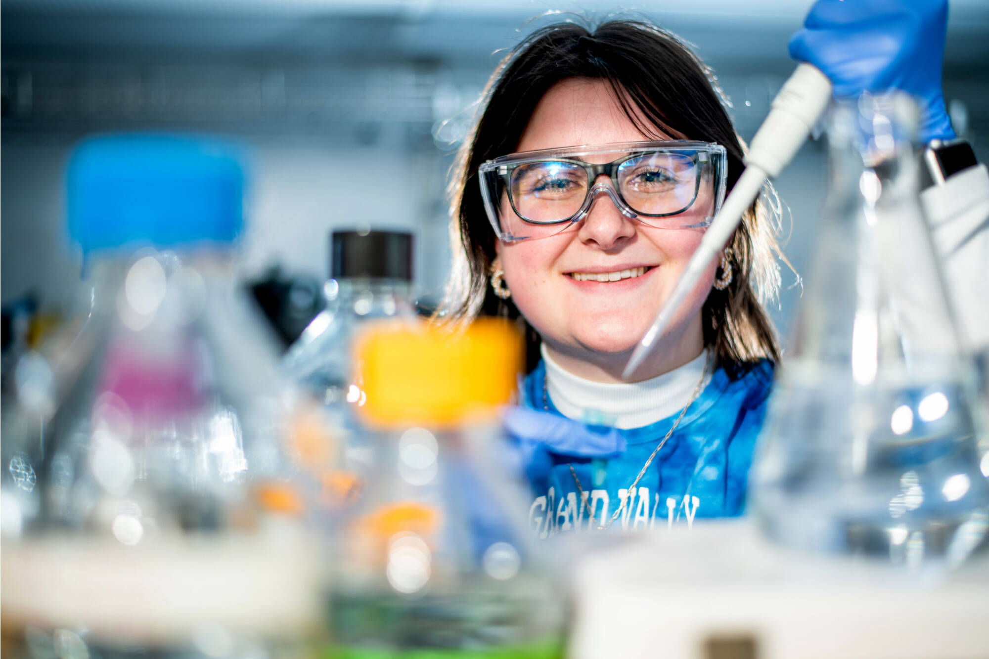 A student smiling while conducting a scientific experiment in a lab